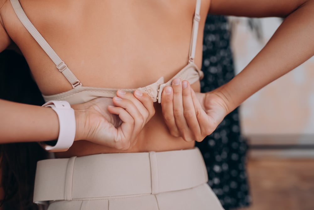 Rear view of a young woman taking off her bra