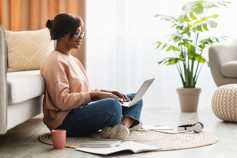 Side View Of African American Female Using Laptop Computer At Home