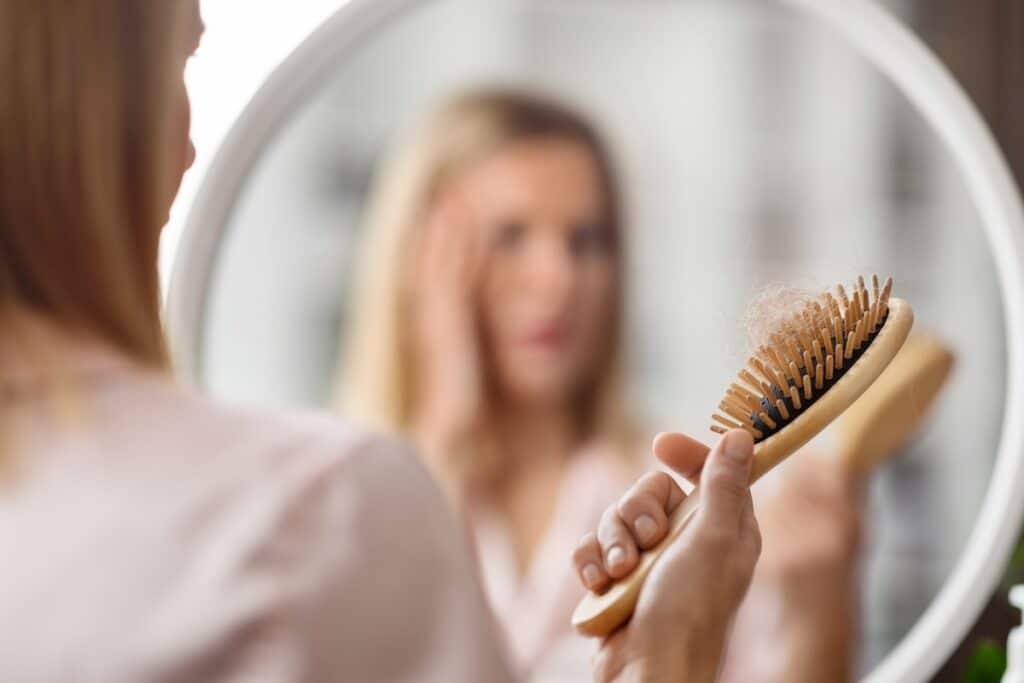 Hairloss. Shocked Blonde Woman Holding Comb Full Of Fallen Hair After Brushing