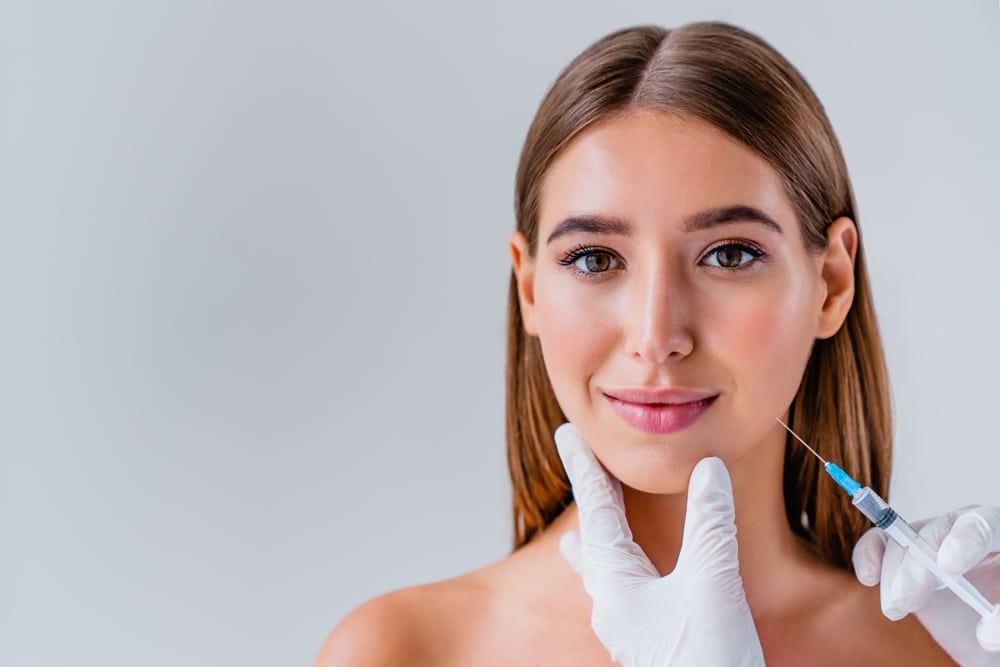 Cosmetic surgeon’s hands about to administer BOTOX into a woman’s face in Tuscaloosa, AL.