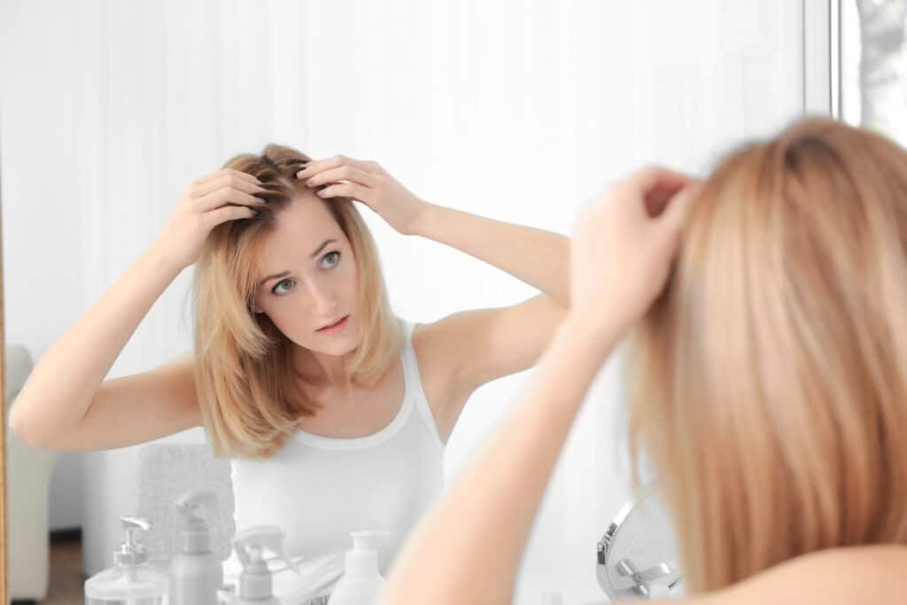Woman checking her hair in the mirror for new growth after starting Nutrafol supplements