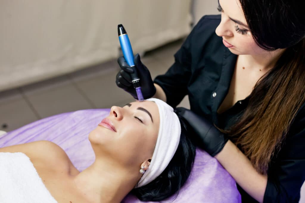 Woman receiving microneedling treatment from her technician for smoother, brighter skin