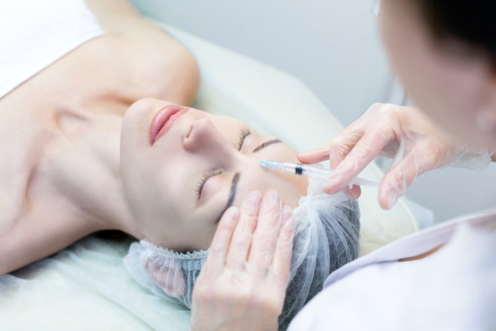 Woman receiving Dysport injections between her brows to smooth forehead wrinkles and prevent fine lines.