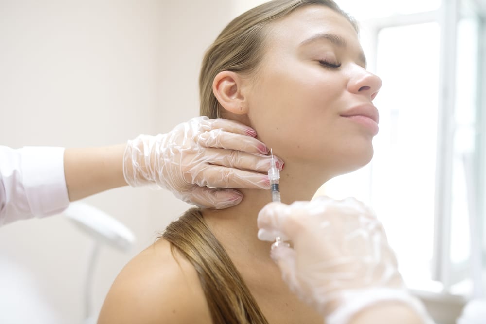 Woman receiving a Botox injection to her jaw to relieve bruxism pain and slim her jawline.
