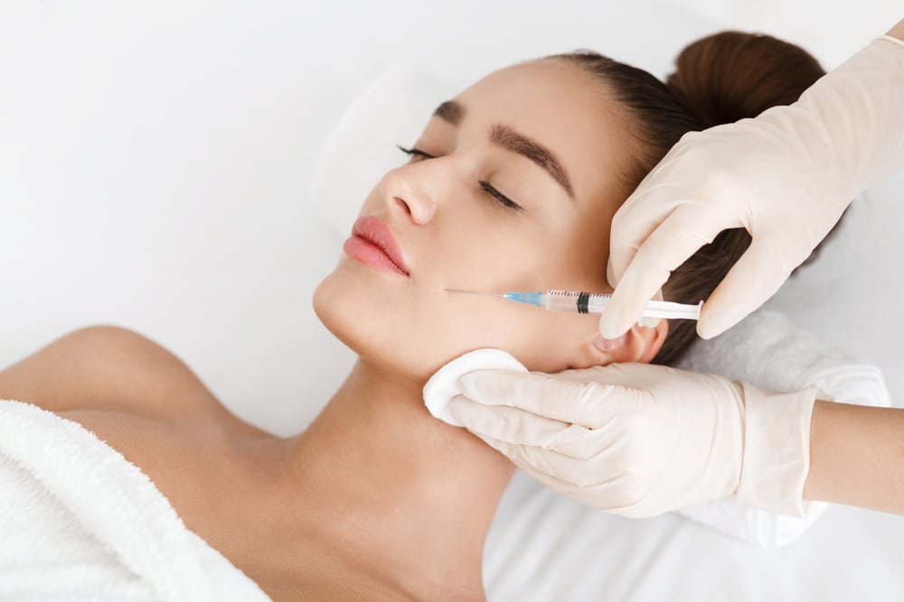 Close up of a woman laying down and receiving Botox injections from her injector.