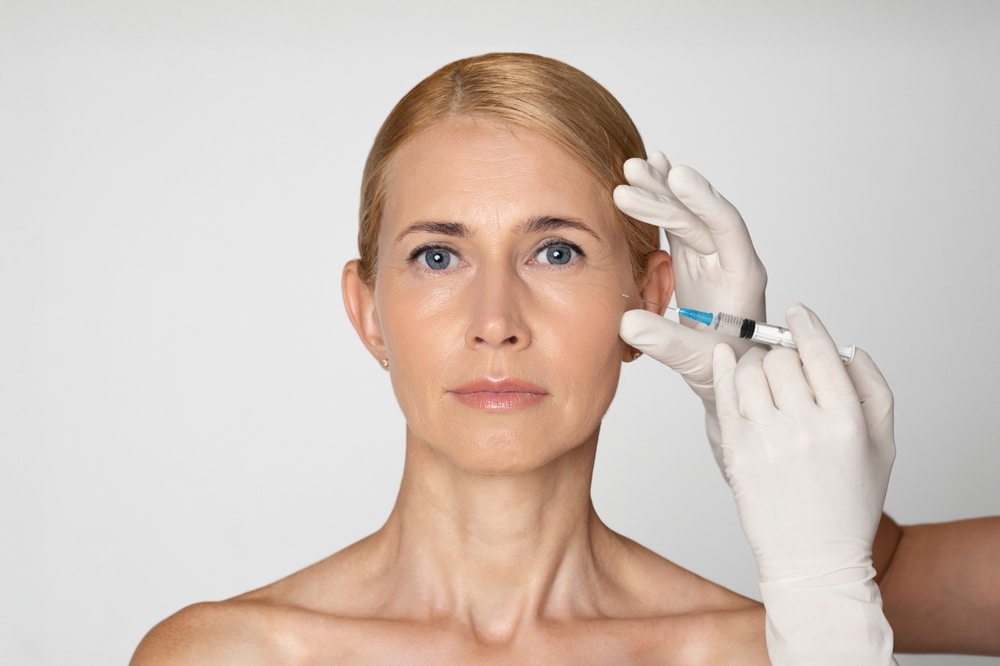 Older minimalist woman receiving Sculptra injections to improve under-eye hollows.