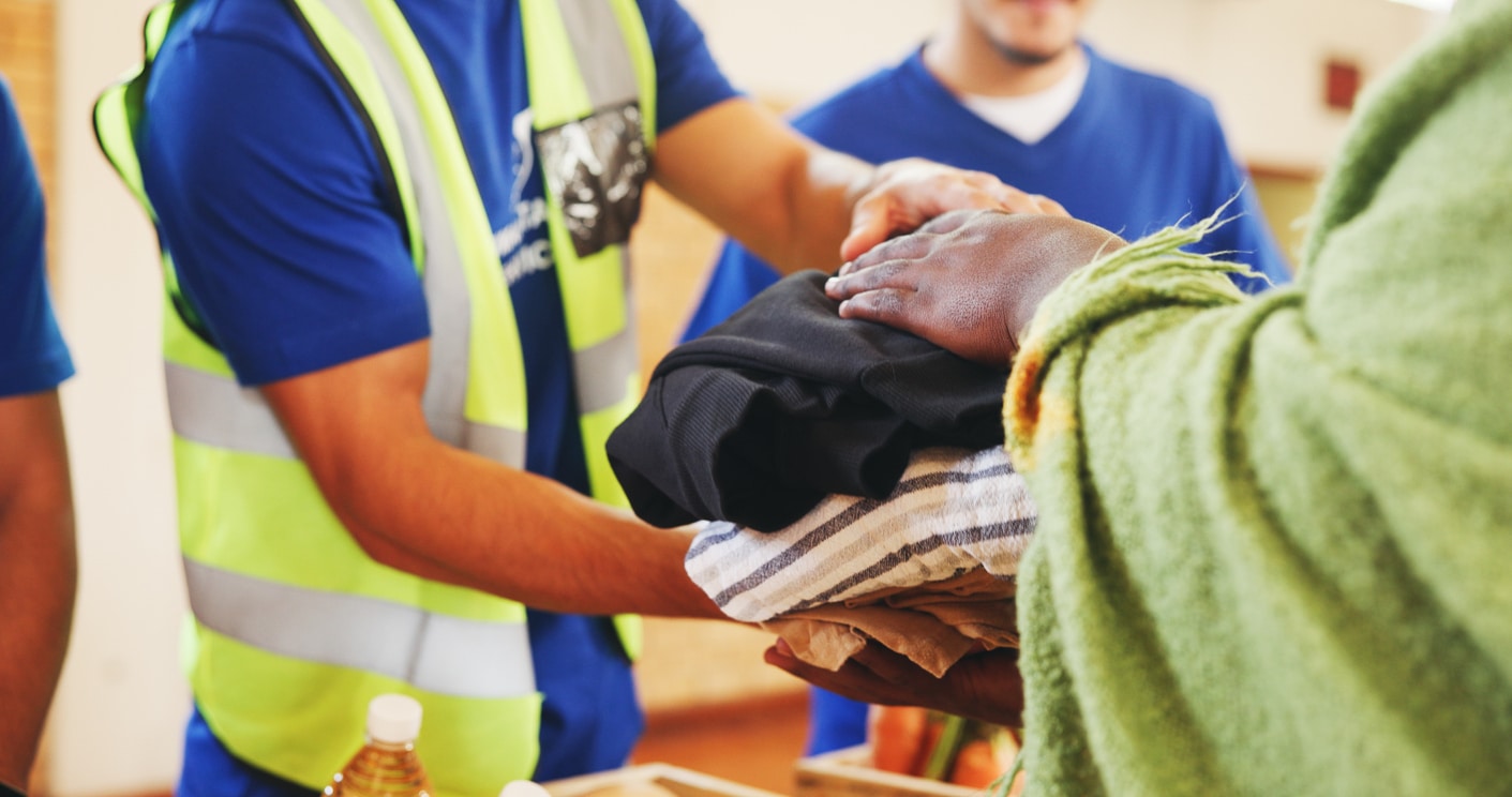 Clothes, help or hands with donation for homeless person, social project or community relief. Charity, group or people giving blankets for humanitarian aid, distribution or winter with support at NGO